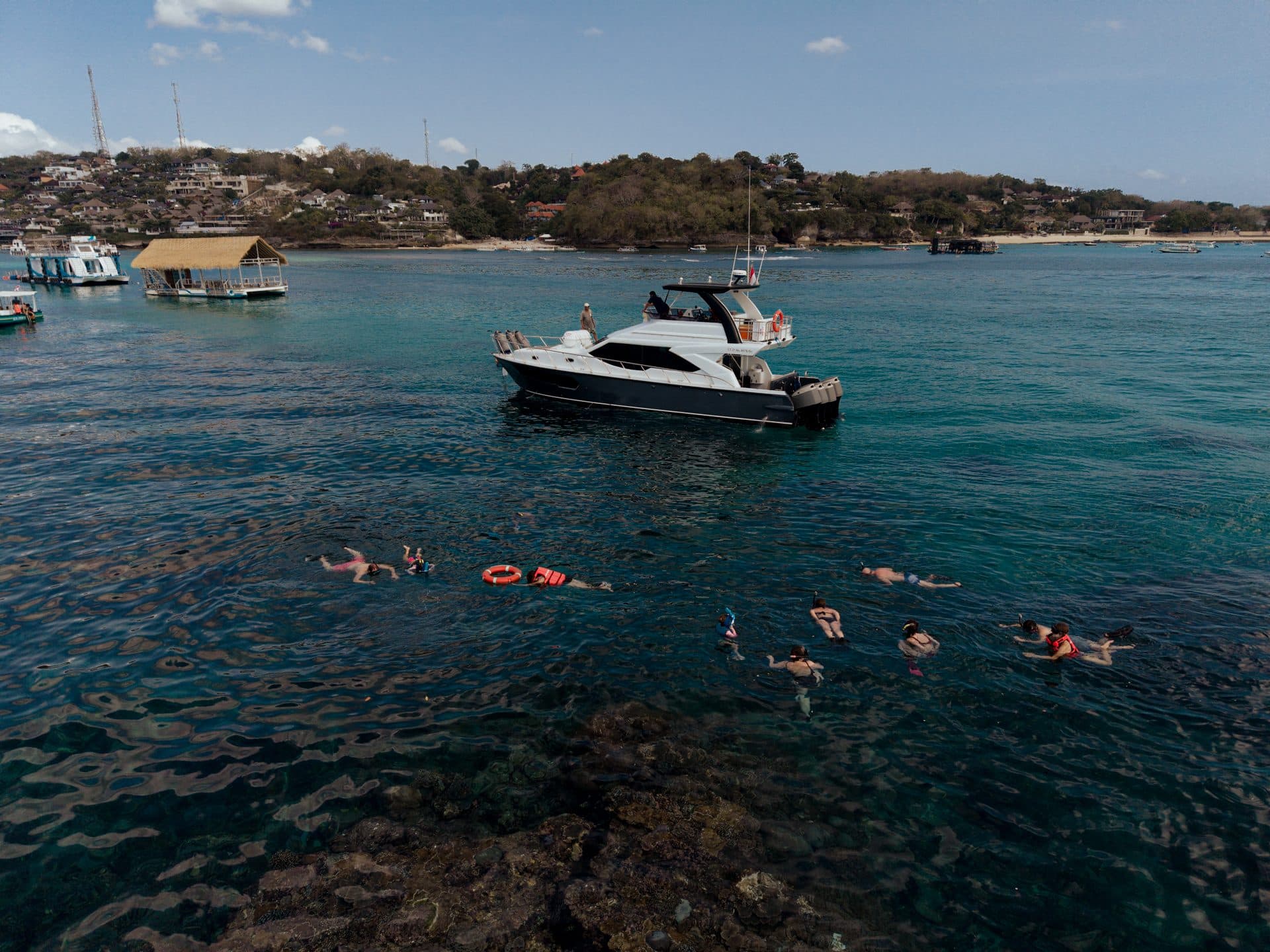 Aerial view of a yacht with guests snorkeling nearby in Bali