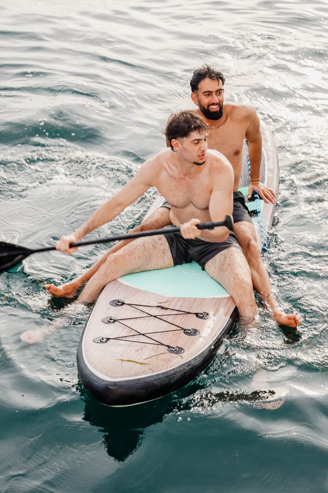 Couple paddleboarding beside the yacht