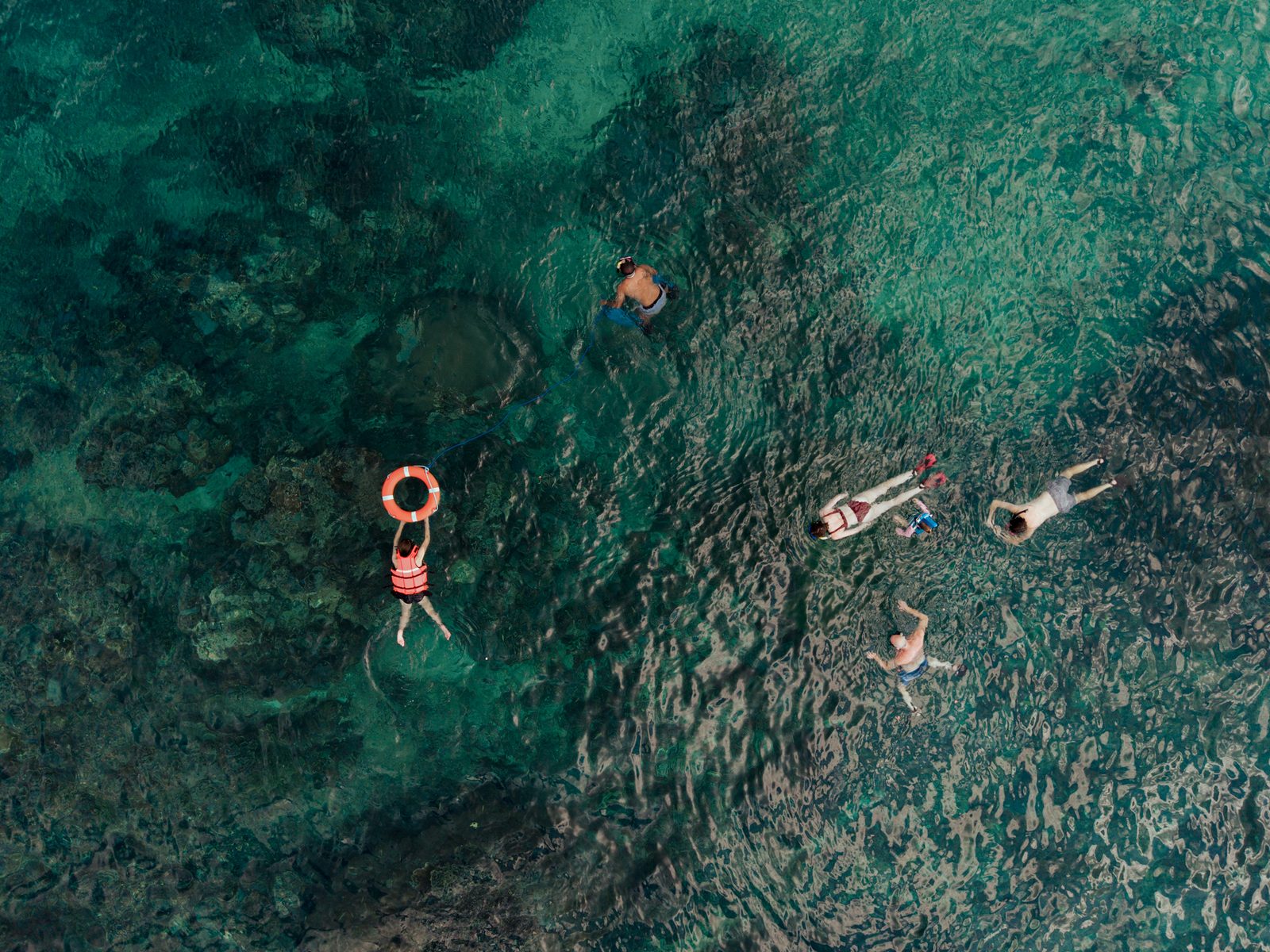 Aerial view of guests snorkeling in turquoise water over a reef in Bali