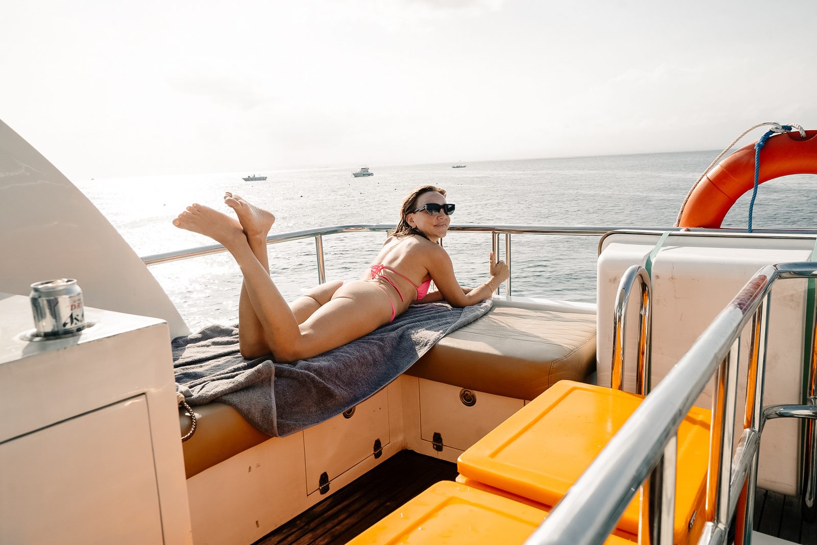 Guest relaxing with a drink on the sun deck of a private yacht in Bali
